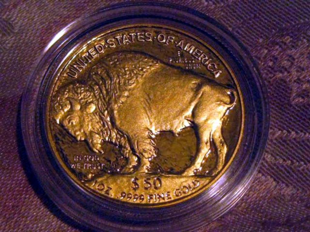 Eine gold- und braune Münze mit der Aufschrift 'The United States Of America' darauf, die auf einer braunen Teppichfläche liegt.