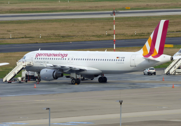 Germanwings Airbus A320-200 am Frankfurt Airport mit Bodenfahrzeugen, Verkehrskegeln, Versorgungsmasten und Grasfläche im Hintergrund.