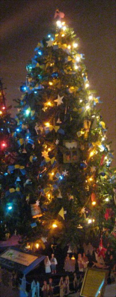 Ein geschmückter Weihnachtsbaum mit darunter platzierten Statuen.