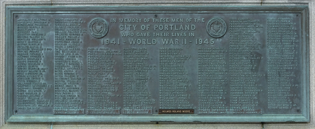 Bronzeplatte an einer Gebäudewand mit der Inschrift "Denkmal für die Stadt Portland" in fetter schwarzer Schrift, eingerahmt von einem dekorativen Rand.