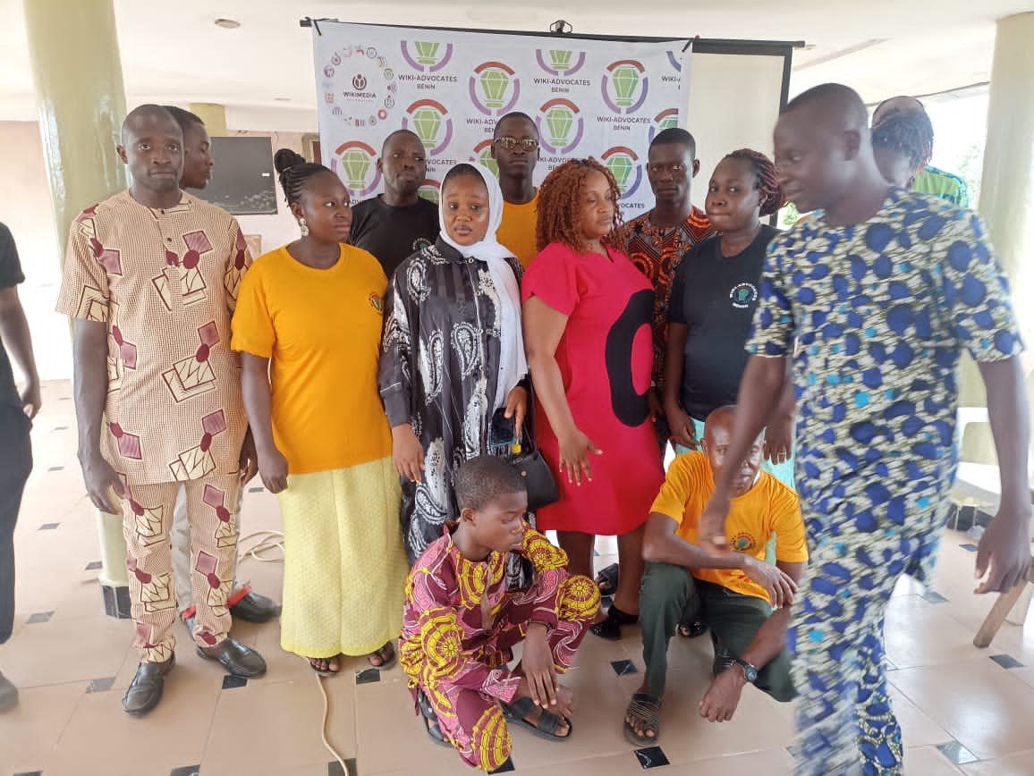 Gruppe von Menschen vor einem Banner mit der Aufschrift "Advocates in Ghana: Ein Schritt-für-Schritt-Führer" mit Stühlen, Säulen, einem Fernseher und Deckenleuchten im Hintergrund.