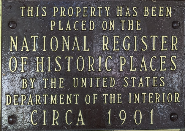 Eine Metalltafel an einem Gebäude mit der Inschrift "Dieses Gebäude wurde in das nationale Verzeichnis historischer Stätten aufgenommen."