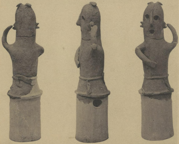 Drei Terrakottastatuen eines Mannes und einer Frau in traditioneller Kleidung, die eng beieinanderstehen und sich um die Schulter fassen.