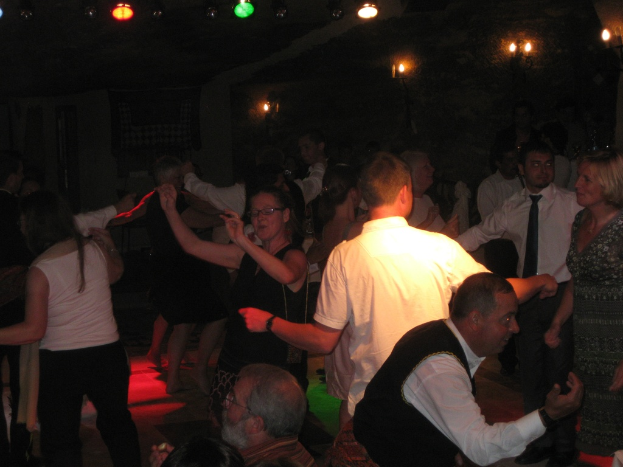 Eine lebendige Partyszene mit tanzenden Menschen auf der Tanzfläche unter einer dunklen Decke, die mit verschiedenen Lichtern geschmückt ist.