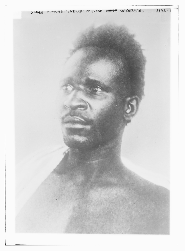 Ein Schwarz-Weiß-Foto eines Mannes mit ernstem Gesichtsausdruck, mit dem Text "Seneg Verletzter französischer Gefangener unter deutscher Herrschaft" oben.