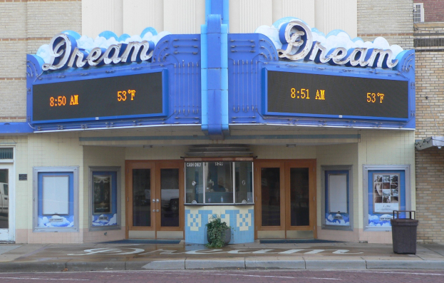 Außensicht des Dream Theaters in St. Louis, Missouri, mit Glastüren und -fenstern, einem Namen-Schild, einem Mülleimer, einem Topf mit einer Pflanze und einer Straße unten.