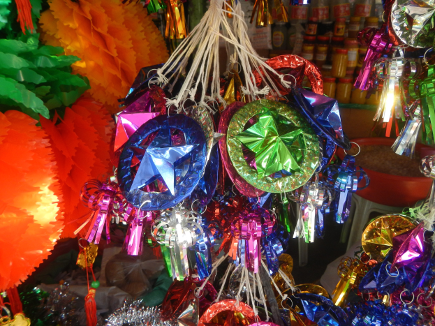 Farbenfrohe Dekorationen wie Papierlaternen und Bänder hängen von der Decke über Regalen voller Flaschen in einer festlichen Atmosphäre.