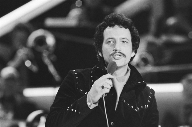 Schwarzes und weißes Foto von Elvis Presley mit einem Mikrofon bei einer Live-Aufführung mit einem unscharfen Hintergrund.