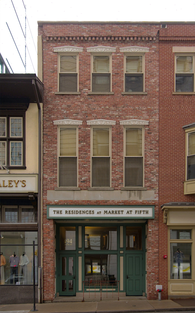 Ladenfront von "Residences at Market at Fifth" mit Glasfenstern und -türen, die Schaufensterpuppen in Kleidern zeigen, vor einem Straßen- und Himmel-Hintergrund.