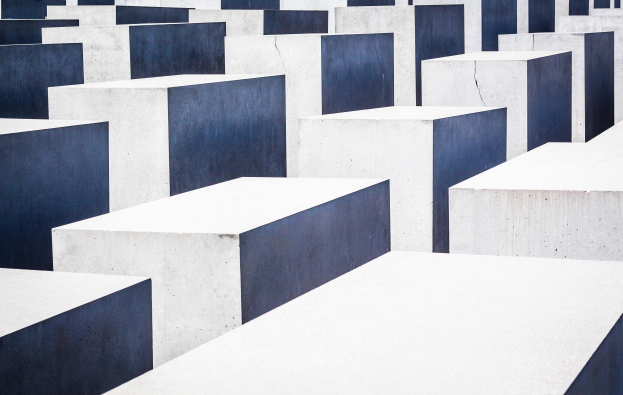 Ein Feld rechteckiger Betonplatten h"{o}herer Gr"{o}ssen, die in einem Gittermuster angeordnet sind, bekannt als Holocaust-Mahnmal f"{u}r die ermordeten Juden Europas, befindet sich in Berlin, Deutschland.