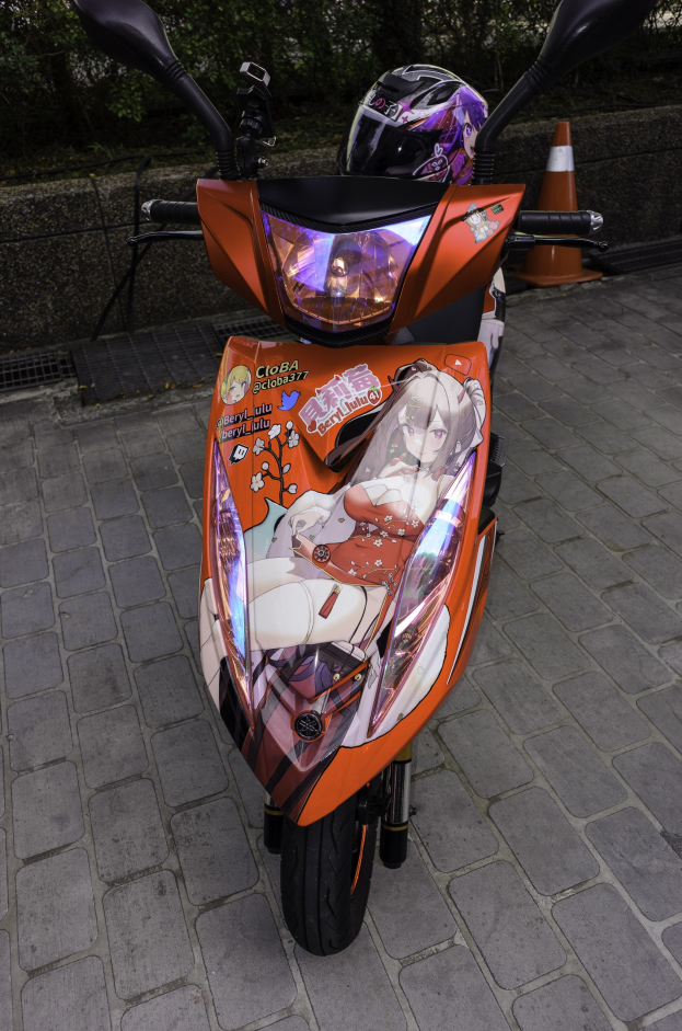 Ein oranges E-Scooter mit einem Helm darauf auf der Seite einer Straße geparkt, mit einem Verkehrskegel, einer Wand und Bäumen im Hintergrund.