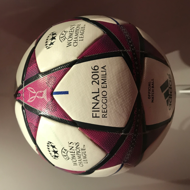 Ein Fußball auf einem weißen Tisch mit der Aufschrift 'UEFA Women's Champions League Final 2016' in Weiß, Rosa und Schwarz.