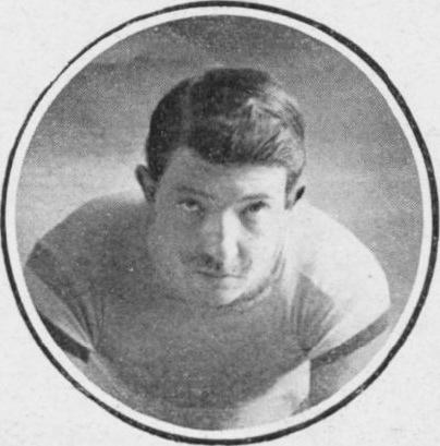 Schwarzes und weißes Foto eines Mannes in einem Fußballtrikot mit ernster Miene, kurzen dunklen Haaren und einem Fußballtrikot.