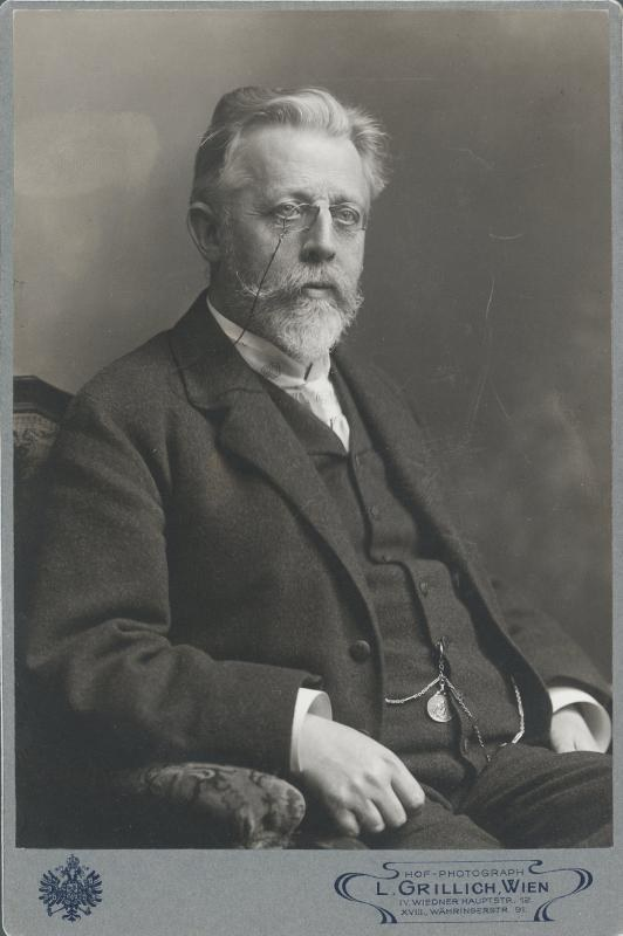 Schwarz-weiß-Fotografie eines bärtigen Mannes mit Brille, der in einem Stuhl sitzt, mit der Überschrift "L. Grillich Wien, der Gründer der deutschen Revolution" unten.