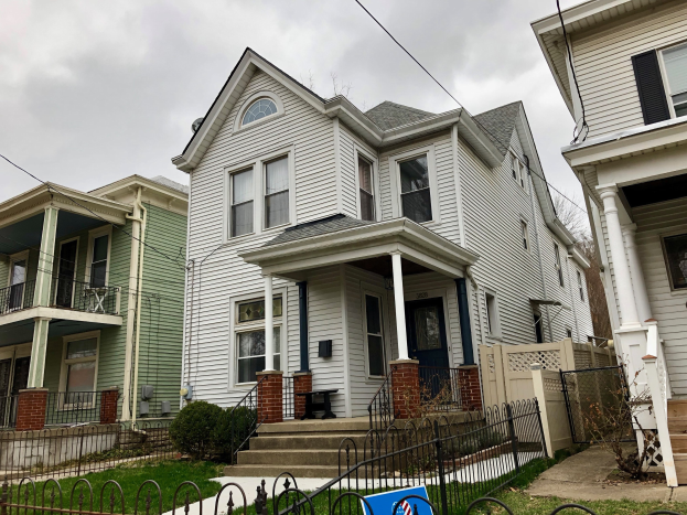 Reihe von Häusern mit Fenstern, Türen, Säulen, Geländern, Stufen und Dächern, umgeben von einem Metallzaun, Gras, Pflanzen, Bäumen und einem bewölkten Himmel, mit einem Mietschild am Boden, das die Immobilie an 5901 S Elmwood Ave, Chicago 60618 anzeigt.