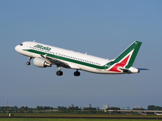 Ein Airbus A320-232 ERJ-EJZ der Alitalia, der vom Frankfurter Flughafen abhebt mit grünem Gras, B├Ąumen, Geb├Ąuden und einem klaren blauen Himmel im Hintergrund.