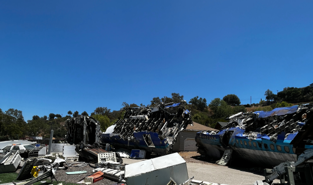 Das Wrack eines Flugzeugs, das in ein Gebäude in San Francisco, Kalifornien, gekracht ist, mit verstreuten Trümmern auf dem Boden und einem klaren blauen Himmel im Hintergrund.