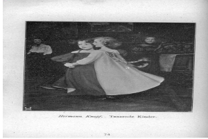 Zwei junge Mädchen tanzen auf einer Bühne vor einem Vorhang, mit einer Person, die links von ihnen auf einem Stuhl sitzt, einer Säule und einer Wand im Hintergrund.