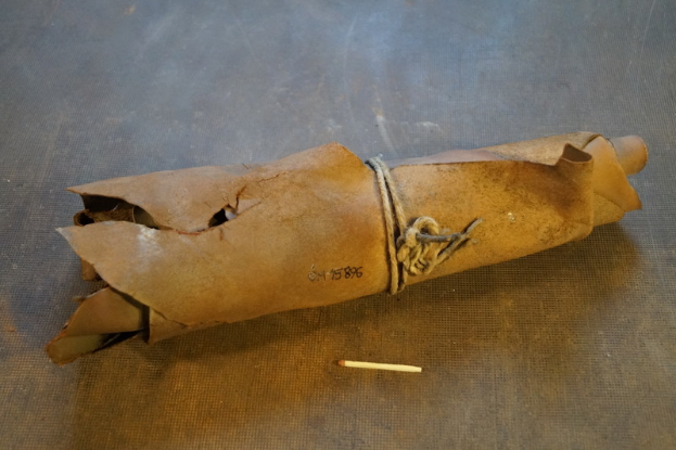 Ein brauner Papiertüte in Form einer Granate mit Griff, mit einem Seil zugebunden und eine Zigarette daneben auf einem Tisch.