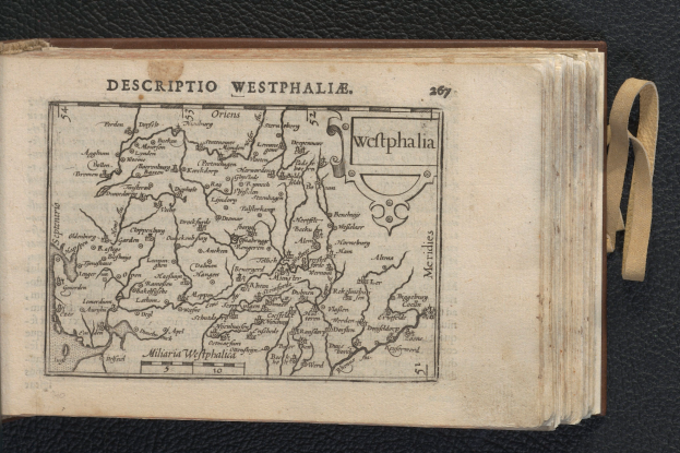 Ein aufgeschlagenes Buch mit einer detaillierten Karte der westfälischen Geographie, das auf einer schwarzen Oberfläche ruht.