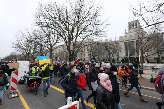 Eine große Gruppe von Menschen marschiert am 21. Januar 2020 in Washington, D.C. mit Schildern und Plakaten, einige fahren Fahrräder, mit Stangen, Bäumen und einem klaren blauen Himmel im Hintergrund.