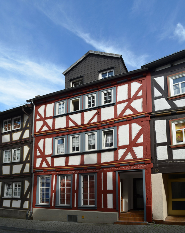 Reihe von Fachwerkhäusern in Heidelbergs Altstadt mit Fenstern, Türen und weißen Wolken am Himmel.