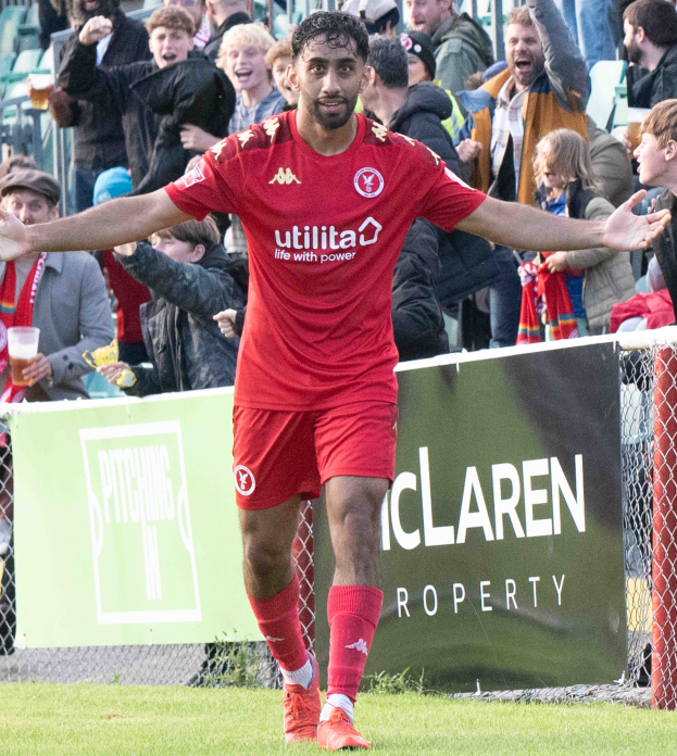 Ein Fußballer in roter Uniform rennt mit ausgestreckten Armen auf einem Feld, im Hintergrund ist eine Menschenmenge zu sehen und ein Banner mit der Aufschrift "Middlesbrough FC v Swansea City - Sky Bet Championship"