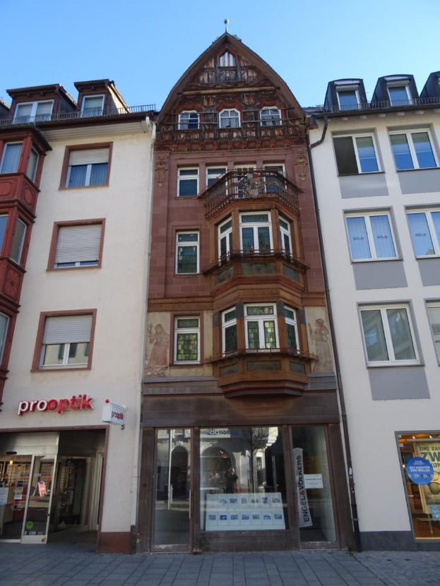 Gewerbliches Immobilienobjekt zum Verkauf in Heidelberg, Deutschland, mit einem mehrfenstrigen Gebäude neben einer Straße unter einem klaren blauen Himmel.
