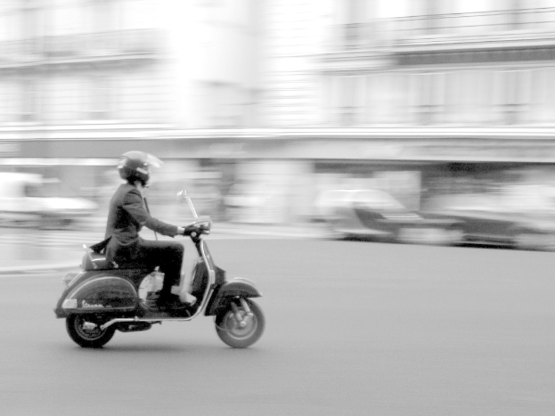 Eine Person fährt mit einem Roller auf einer Straße.