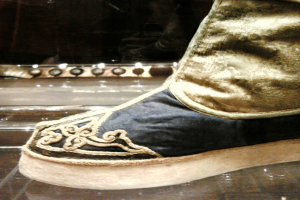 Nahaufnahme eines Schuhpaares in einer Glasvitrine auf einem dunklen Boden.