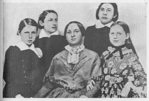 Ein Schwarz-Weiß-Foto einer vielfältigen Gruppe von Frauen, mit einer sitzend in der Mitte und Text unten mit der Aufschrift "Die Frauenwahlrechtsbewegung".