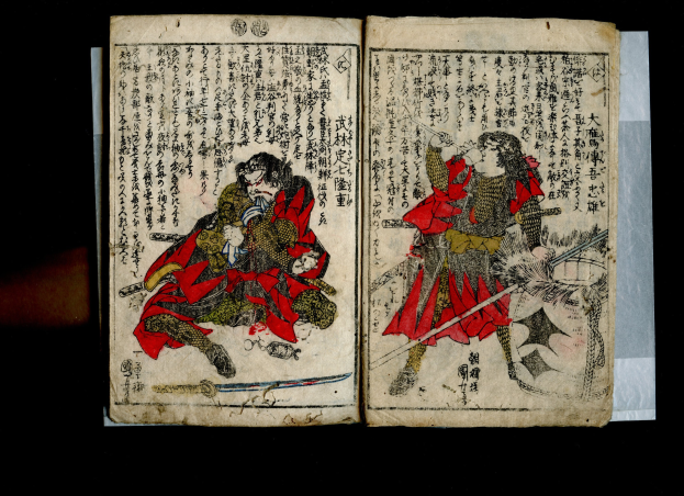 Offenes Buch mit dem Titel "Utagawa Kunisada Toyokuni III/Kuniyoshi Toyokubi III" aus der Serie *Fünfzig-drei Stationen der Tokaido*, das eine detaillierte Illustration von zwei Samurai-Kriegern zeigt, die mit gezückten Schwertern in einen heftigen Kampf verwickelt sind.