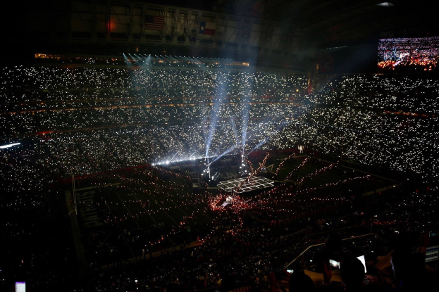 Gro├če Menge in einem hell erleuchteten Stadion bei Nacht, mit einem Bildschirm auf der rechten Seite, der die Ergebnisse der Super Bowl XLVII-Halbzeitpause anzeigt.