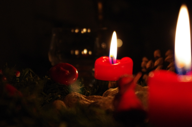 Mehrere rote Kerzen brennen und strahlen Licht und Rauch aus.