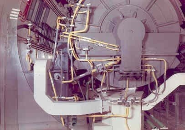 Großes industrielles Beschleunigergerät mit mehreren verbundenen Komponenten und Kabeln innerhalb eines Gebäudes.