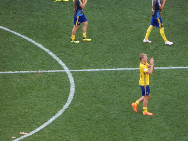 Mannergruppe in Fußballtrikots auf einem Fußballfeld, die jubeln.
