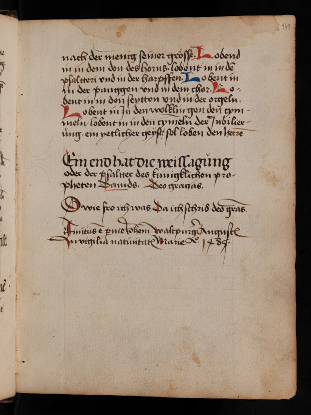 Ein aufgeschlagenes Buch mit schwarzem Hintergrund zeigt eine Seite aus einem Manuskript des 15. Jahrhunderts mit roter und schwarzer Schrift.