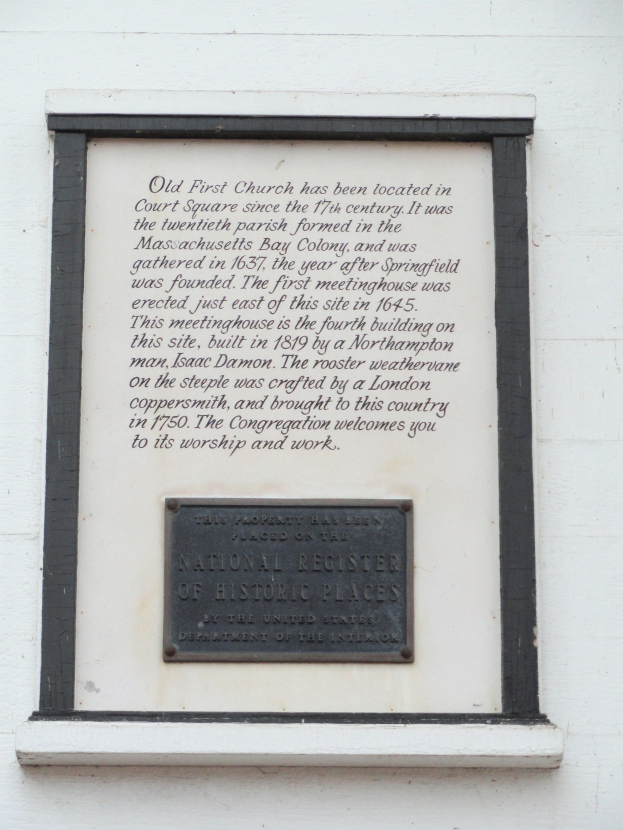 Plaque auf einer Gebäudewand mit der Aufschrift "National Register of Historic Places" in fetter Schrift, umgeben von einem dekorativen Rahmen, auf dunklem Material montiert.