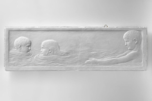 Schwarzes und weißes Foto von drei Kindern, die im Wasser schwimmen, mit einer Wand im Hintergrund, mittig im Bild.