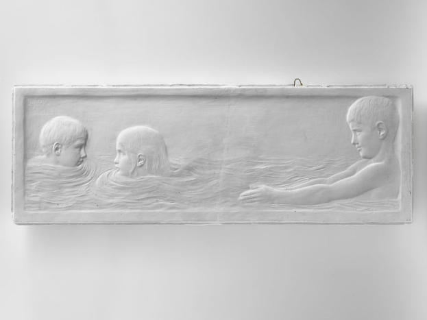 Schwarzes und weißes Foto von drei Kindern, die im Wasser schwimmen, mit einer Wand im Hintergrund, mittig im Bild.