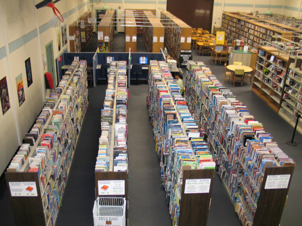 Eine Bibliothek mit Regalen voller Bücher und Tischen und Stühlen vor einer Wand.